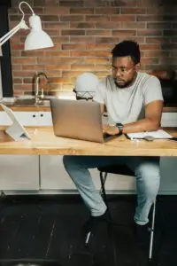 African American man working on a laptop in his home office setting, focusing on remote work tasks.